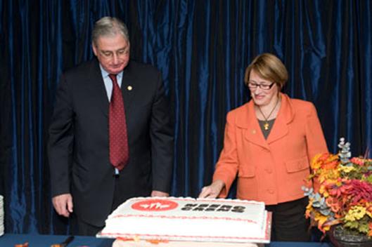 Hon. James Edwards and Dr. Suzanne Fortier prepare to serve cake to staff at the 100th Council Meeting reception
